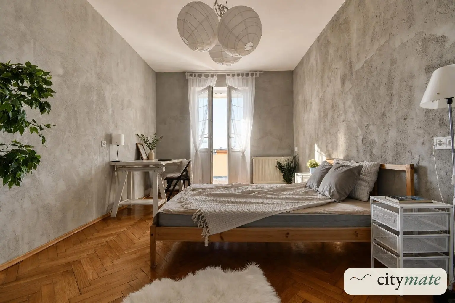 Umeblowana sypialnia z łóżkiem, biurkiem i wyjściem na balkon